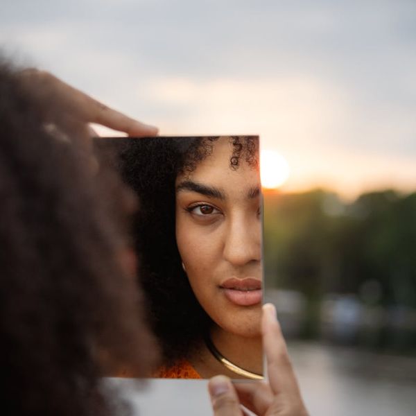 Person meditating peacefully outdoors with soft focus background.